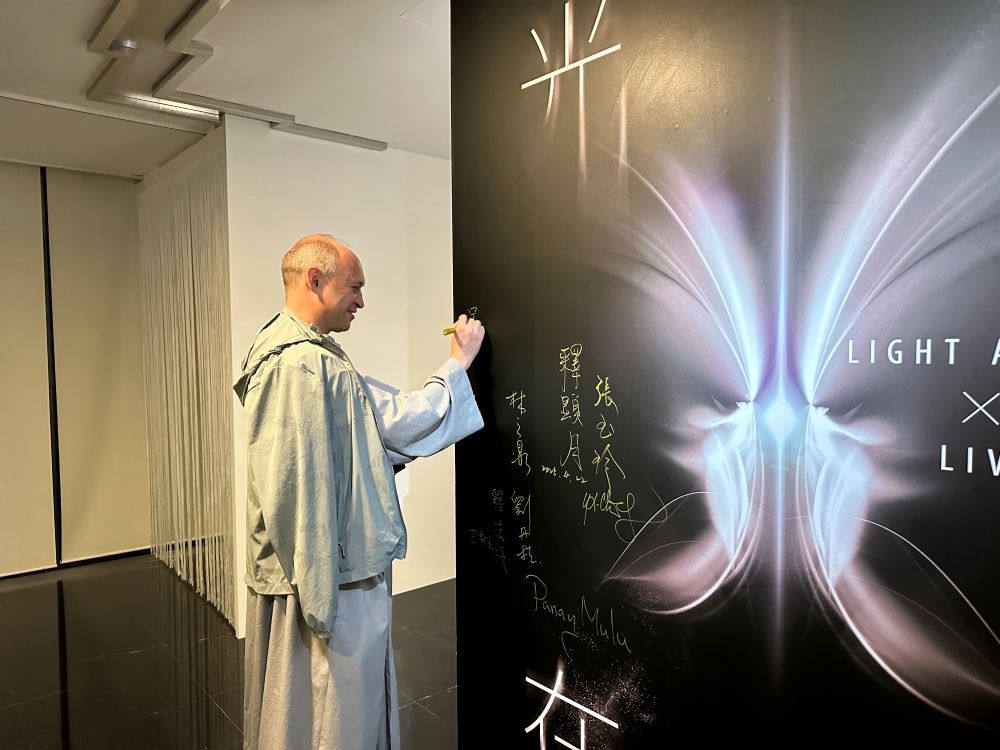 光在萬物 神職人員參訪宗博館深感希望啟示 3 《圖說》呂天恩神父在「光在萬物」特展展板上簽名。〈宗博館提供〉