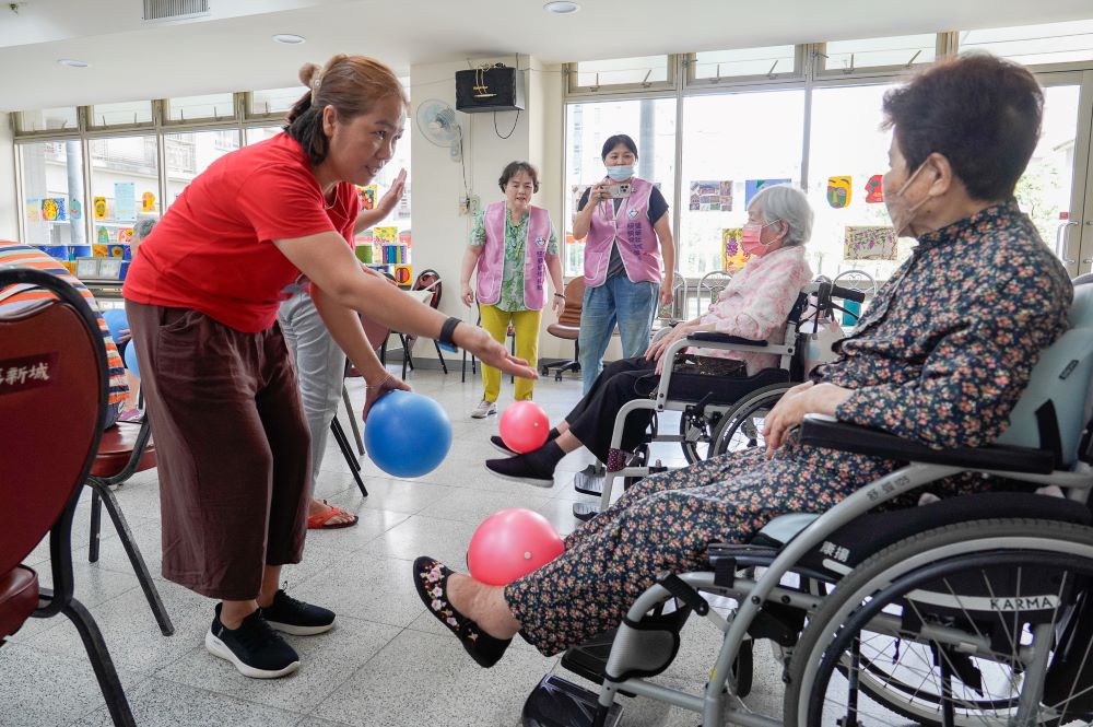 擁有晚美人生 板橋健華新城社區照顧關懷據動靜皆宜 2 《圖說》志工鼓勵長輩用力讓下肢可以伸展抬起球來。〈社會局提供〉