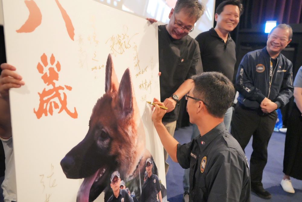 慶祝警察節獻禮 新北《八歲K9》首映會慰勞同仁 3 《圖說》警犬隊長馬清基於大型海報簽名。〈警察局提供〉