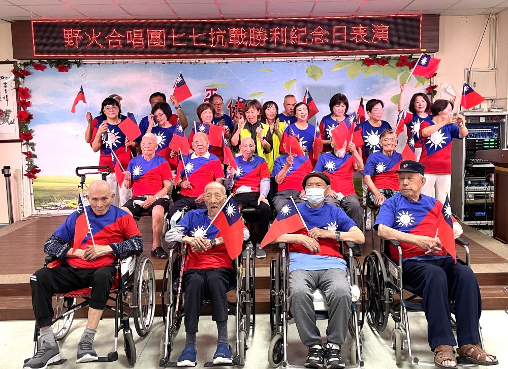 板橋榮家紀念七七80周年 向十位抗戰英雄致敬 2 《圖說》板橋榮家陳桂美主任(中,穿著黃背心)與野火合唱團為10位抗日長輩獻唱「藍天白雲、桃花舞春風」。〈板橋榮家提供〉