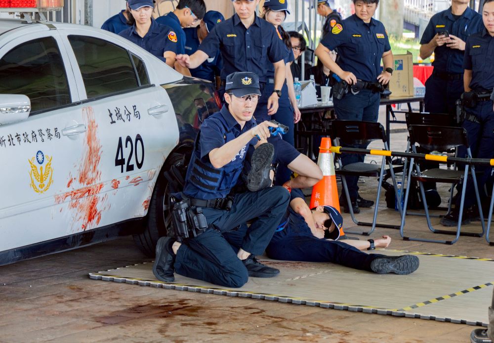 《圖說》新北市警察局情境模擬挑戰過程中員警於執勤中發現現場有警力受傷大出血，一人持槍警戒另一人使用止血帶，進行戰傷救護。〈警察局提供〉