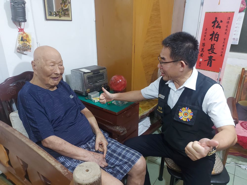 《圖說》臺北市榮服處長黃信仁關懷榮民長輩生活近況，探視百歲榮民汪佛生稱讚養生有道。〈臺北市榮服處提供〉